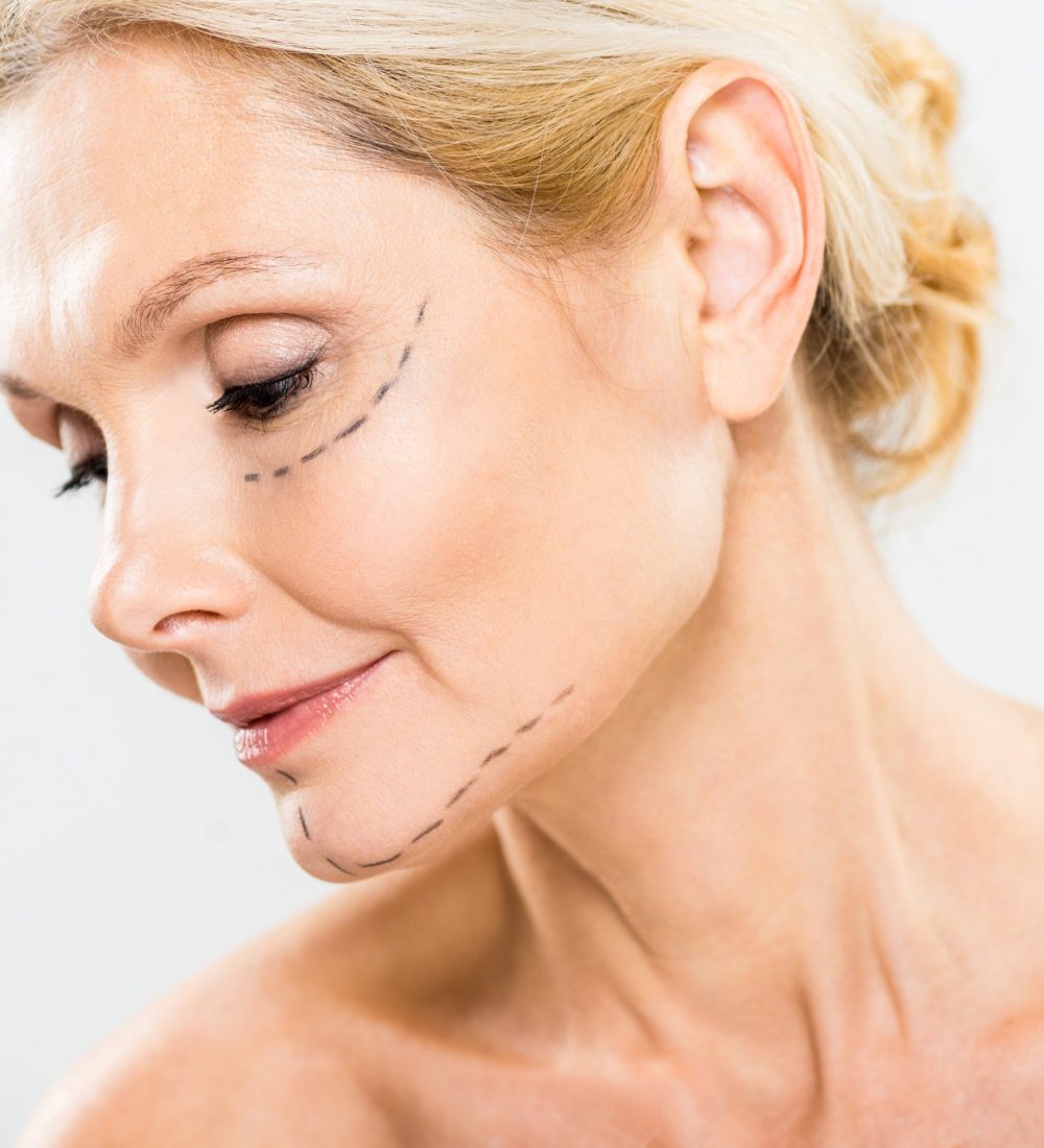 beautiful and middle aged woman with lines on face looking down on grey background